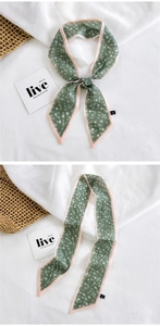 Detailed macro view of green floral skinny scarf tied as a decorative handle wrap for handbags