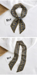 Detail of yellow floral skinny scarf tied as a bow on a textured natural background