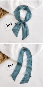 Detailed view of dark green checkered skinny silk scarf used as a stylish hair tie