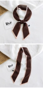 Macro view of herringbone twilly scarf with pink contrast edges on linen background