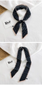 Detail of a grey patterned silk twilly scarf tied in a bow on textured white linen