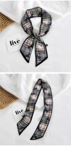 Detail of a black and white twilly scarf with horse patterns and plaid lines on linen