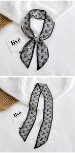 Detailed view of long narrow silk scarf with gray leaf print and tapered ends on white fabric
