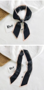 Macro detail of narrow black silk scarf with white script print and pink stitched edges