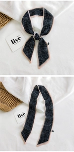 Close-up of narrow silk scarf featuring black spiderweb print and pink edges on linen