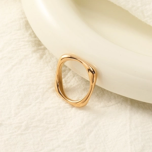 Macro shot of gold-plated stainless steel geometric ring with irregular wavy edges