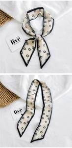 Detail of thin patterned silk scarf showing double-sided print and fine black hem edges