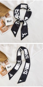 Detail of a black and white cow print long silk scarf tied on a handle with soft lighting