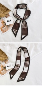 Detail of thin silk scarf with houndstooth pattern and fashion lettering on white fabric