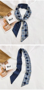 Detail of a navy blue plaid narrow scarf with grid patterns used as a stylish hair tie