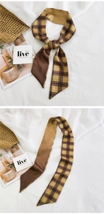 Macro view of vintage brown plaid silk-feel scarf on white fabric with woven basket