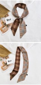 Detailed view of a brown plaid skinny scarf and hair tie styled on a woven basket