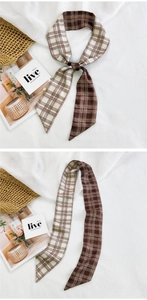 Detail of a brown and white checkered narrow scarf used as a stylish bag accessory