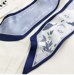 Macro shot of long silk scarf detail with floral prints and gradient blue lettering