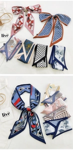 Macro view of assorted printed silk twilly scarves on white fabric and straw bag