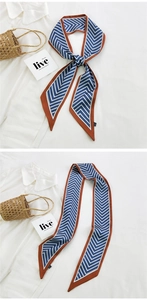 Detail of blue chevron skinny silk scarf with orange contrast border on straw bag