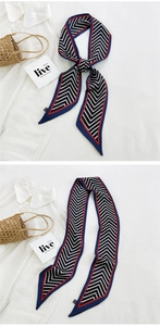 Detail of navy blue and red chevron silk scarf tied on a bag handle and shirt