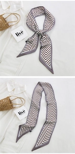 Detail of V-pattern chevron silk scarf tied on a handbag with French style accessories
