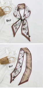 Macro detail of long floral silk scarf tied elegantly on a woven basket handle
