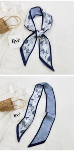 Close-up of a floral blue and white silk scarf tied in a bow on a white shirt