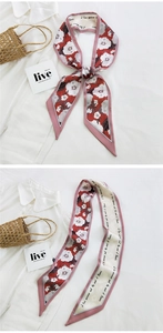 Detail of floral skinny scarf tied on a straw bag handle with hibiscus flower pattern