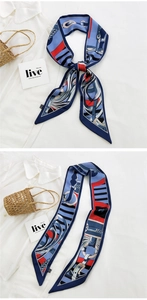 Detail of equestrian print long skinny scarf tied on a straw bag and white shirt