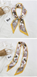 Detail of slim silk scarf with crane and lotus print tied on a straw bag handle