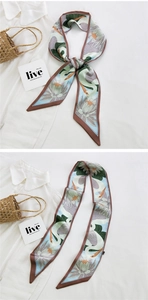 Detail of elegant floral silk scarf with crane pattern tied on a straw bag handle