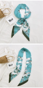 Detail of teal silk twilly scarf with white horse pattern tied on a straw basket handle