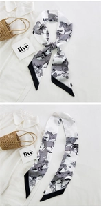 Detail of a horse print silk twilly scarf styled on a white shirt with diagonal ends