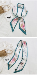Detail of a patterned silk scarf tied on a handbag handle and shown with a white shirt