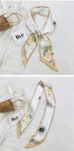 Detail of a beige skinny silk scarf with celestial sun and moon prints on a shirt