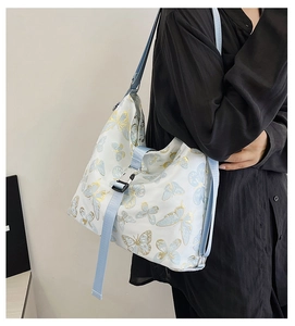 Close-up of white shoulder bag featuring light blue butterfly print and buckle detail