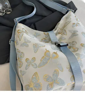 Detailed close-up of blue butterfly patterns and adjustable buckle on the shoulder bag