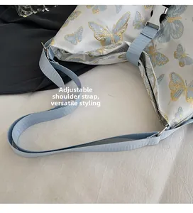 Detail of adjustable shoulder strap and golden butterfly embroidery on white bag