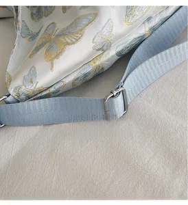 Detail of blue butterfly pattern bag featuring an adjustable silver metal strap buckle
