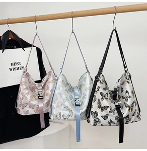 Three fashion butterfly print shoulder bags with adjustable straps hanging on a wooden rod