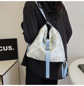 Detail of blue butterfly prints on white nylon bag with adjustable light blue shoulder strap