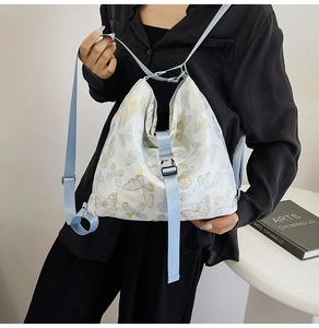 Detail of fashion white backpack featuring blue and gold butterfly prints with metal buckle
