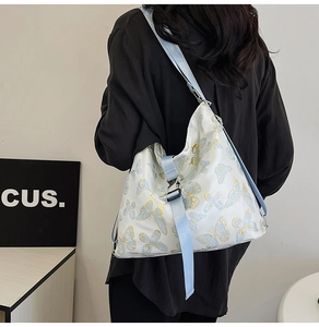 Detail of white shoulder bag with blue butterfly print and adjustable wide fabric strap