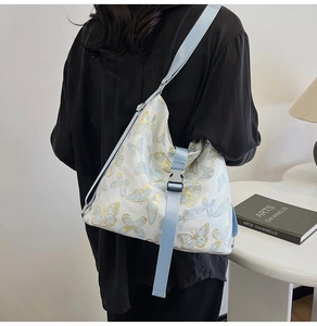 Detail view of large floral shoulder bag with blue butterfly print and adjustable strap