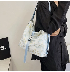 Detail of elegant butterfly print tote bag with adjustable light blue strap on a model