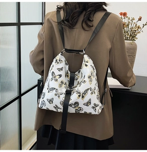 Detail of white backpack featuring elegant black and gold butterfly prints on female model