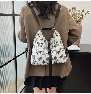 Macro detail of white backpack with elegant black and gold butterfly print and fabric strap