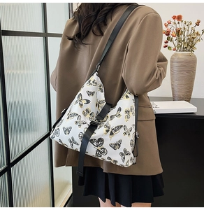 Detailed side view of white crossbody bag with butterfly patterns and adjustable black strap