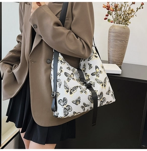 Close-up of stylish white crossbody bag featuring elegant black and gold butterfly prints