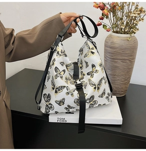 Detailed shot of white tote bag with black and gold butterfly print and buckle closure