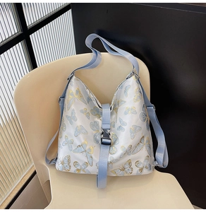 Close-up of blue and gold butterfly print with adjustable buckle on white shoulder bag