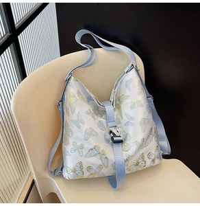 Close-up of light blue butterfly print tote bag resting on a cream-colored chair