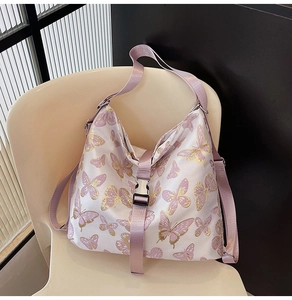 Detail of pink satin shoulder bag featuring floral butterfly prints and buckle closure